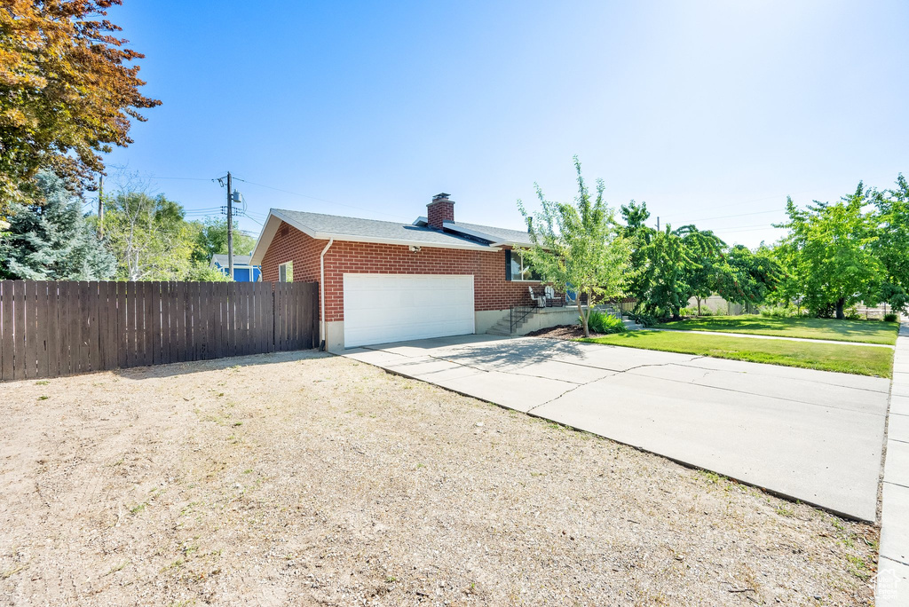 View of home\'s exterior featuring driveway, an attached garage, and a chimney