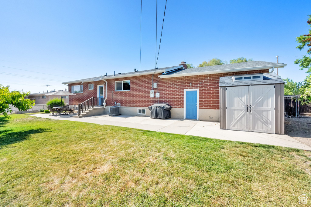 Back of property featuring a patio area, a yard, brick siding, and central AC