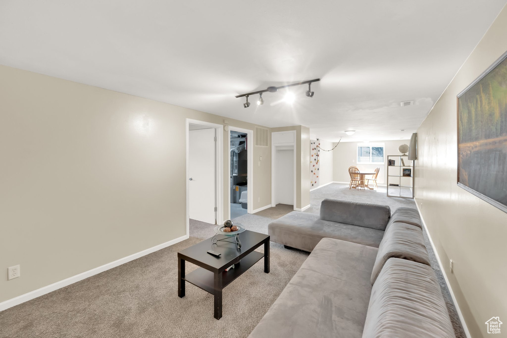 Carpeted living room featuring rail lighting and baseboards