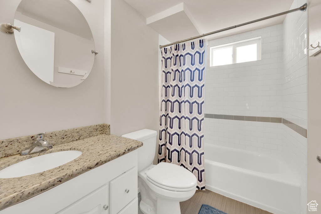 Full bathroom featuring toilet, vanity, and shower / tub combo with curtain