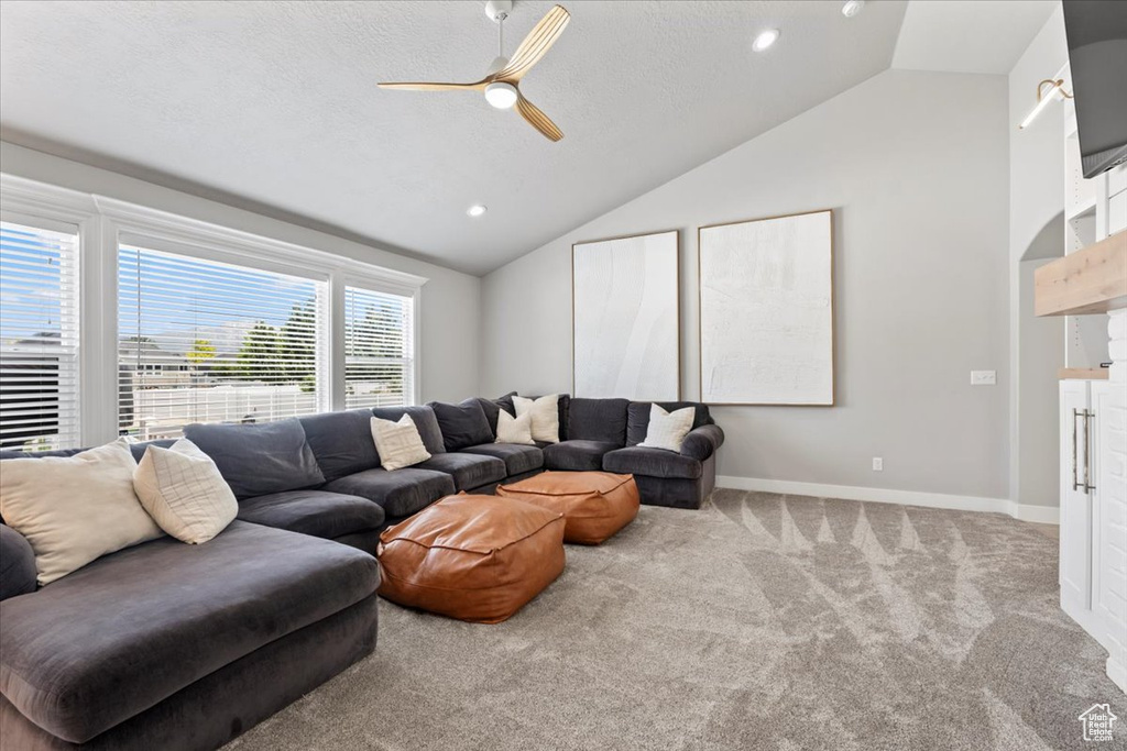 Carpeted living area featuring lofted ceiling, ceiling fan, baseboards, and recessed lighting