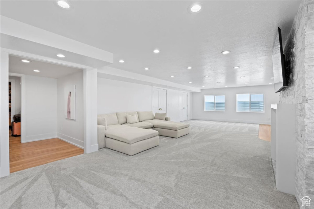Living room featuring carpet floors, recessed lighting, baseboards, a fireplace, and wood finished floors