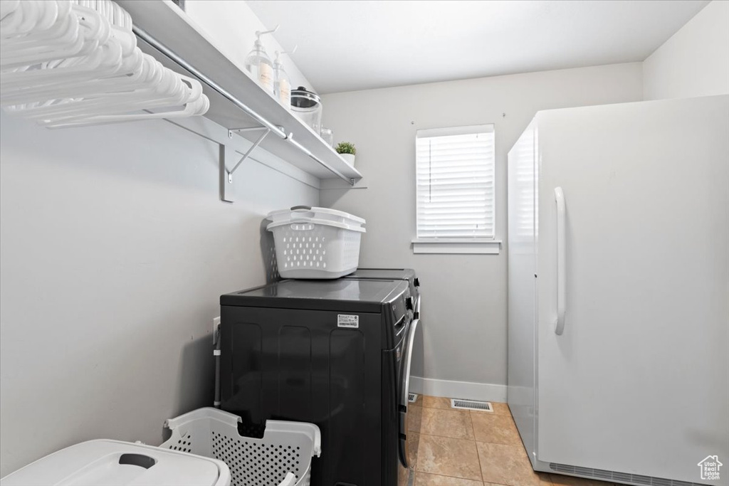 Laundry area featuring separate washer and dryer, baseboards, and light tile patterned floors