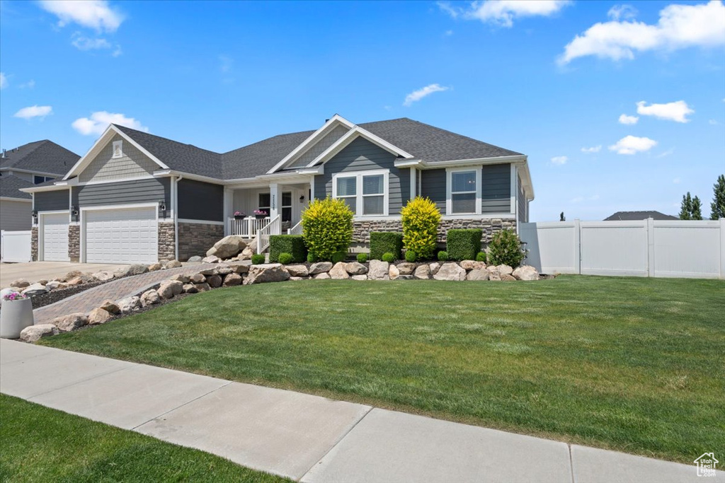 View of front of house with stone siding, a garage, driveway, and covered porch