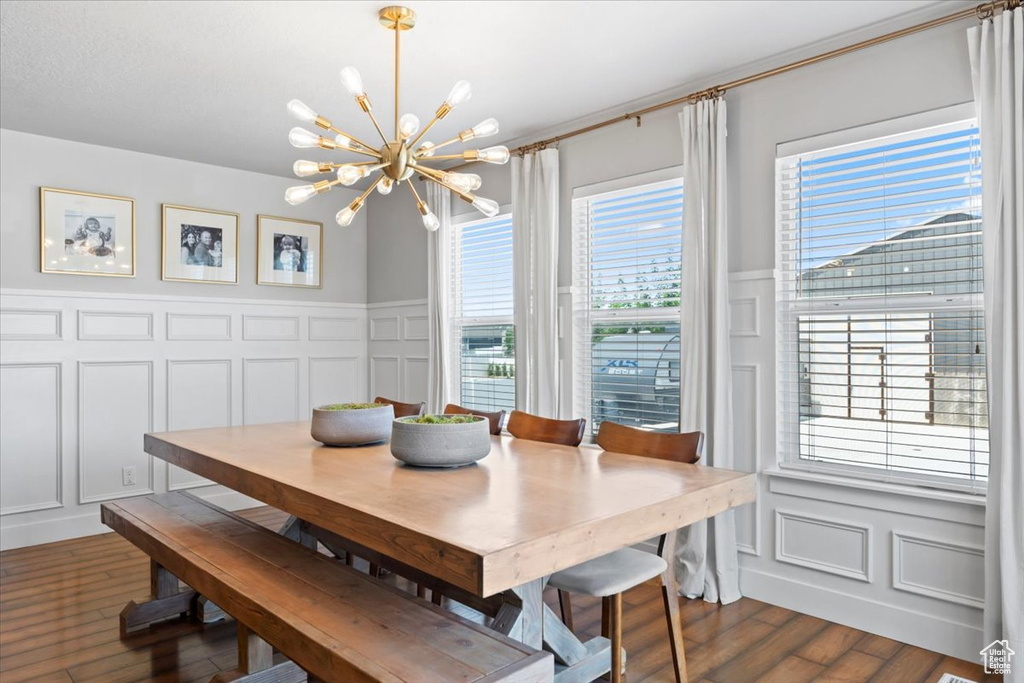 Dining room with a decorative wall, a chandelier, dark wood-style floors, and a wainscoted wall