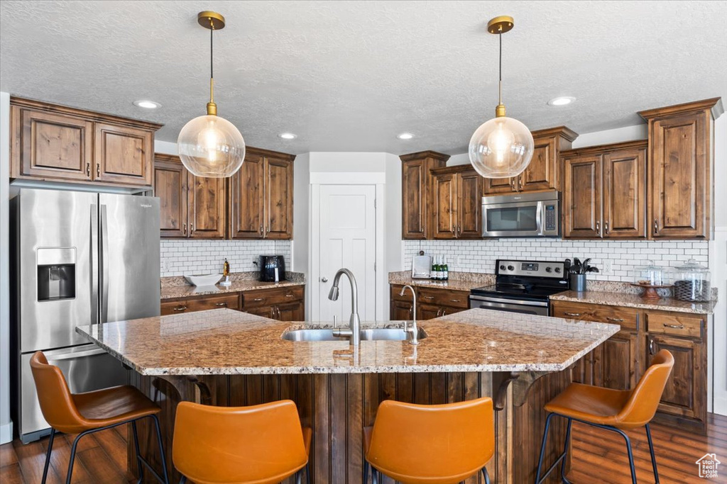 Kitchen featuring stainless steel appliances, a sink, dark wood finished floors, decorative backsplash, and a textured ceiling