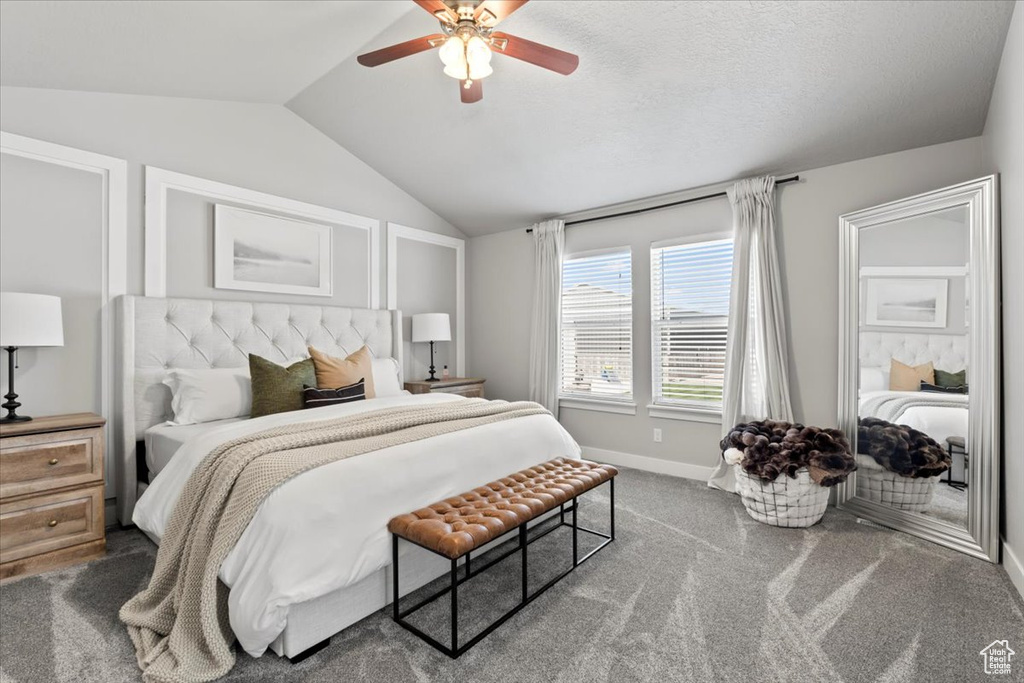 Carpeted bedroom with vaulted ceiling, baseboards, and a ceiling fan