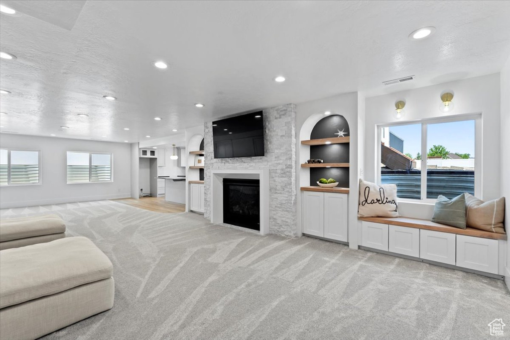 Living room featuring light colored carpet, recessed lighting, a large fireplace, and built in shelves