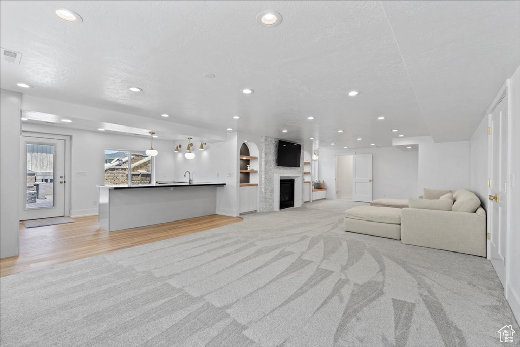 Living room with recessed lighting, light carpet, light wood-style floors, built in shelves, and baseboards