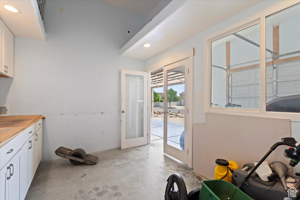 Kitchen with concrete floors, white cabinets, recessed lighting, and french doors