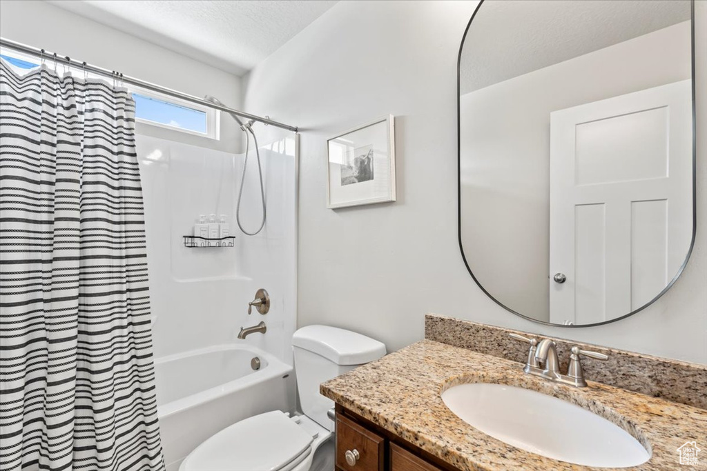 Full bathroom featuring shower / bath combination with curtain, vanity, and toilet