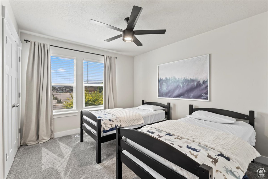 Bedroom featuring light carpet, a textured ceiling, a ceiling fan, and baseboards