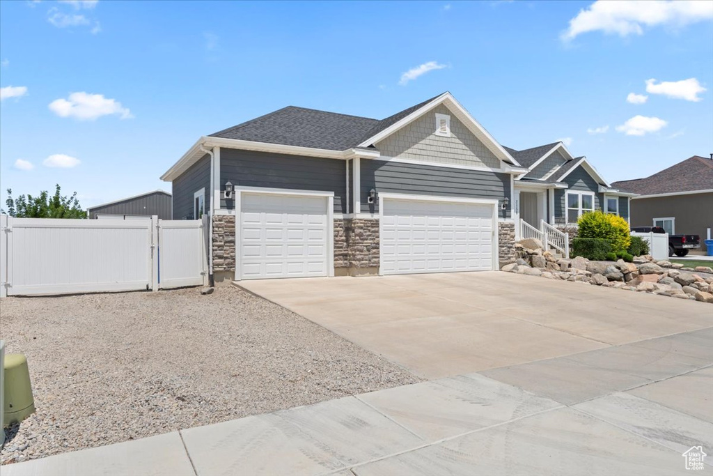 View of front of home with a garage, a gate, stone siding, and concrete driveway