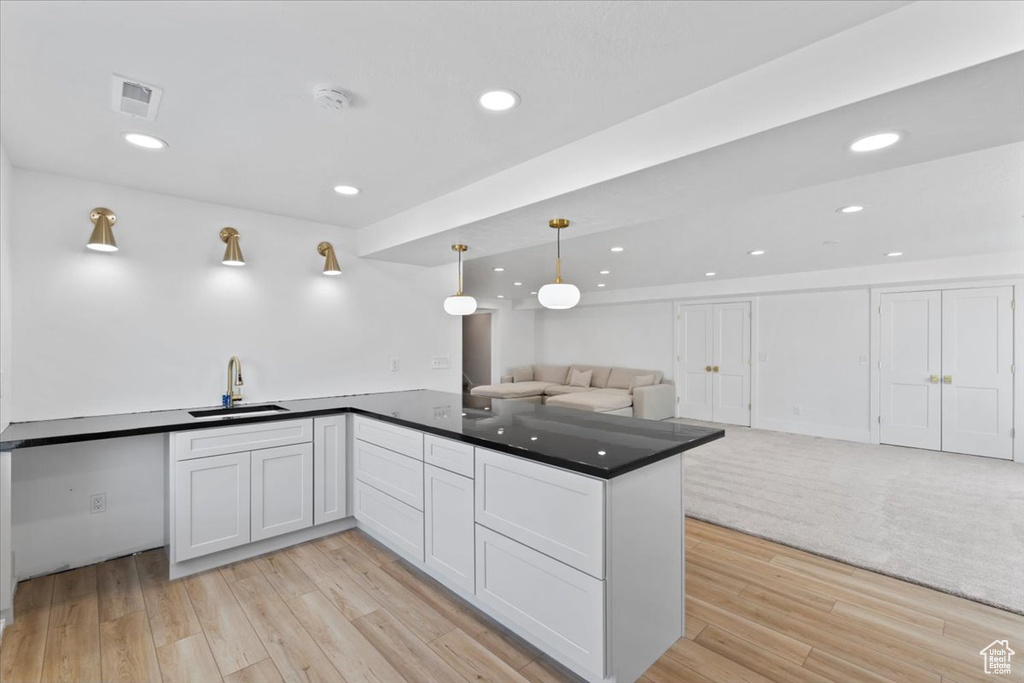 Kitchen with a sink, open floor plan, dark countertops, light wood finished floors, and recessed lighting