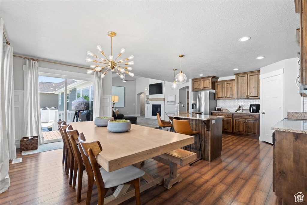 Dining area featuring dark wood-style floors, recessed lighting, a chandelier, and a textured ceiling