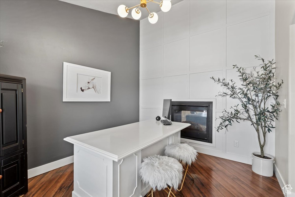Office area with dark wood-style flooring, baseboards, a glass covered fireplace, and a chandelier