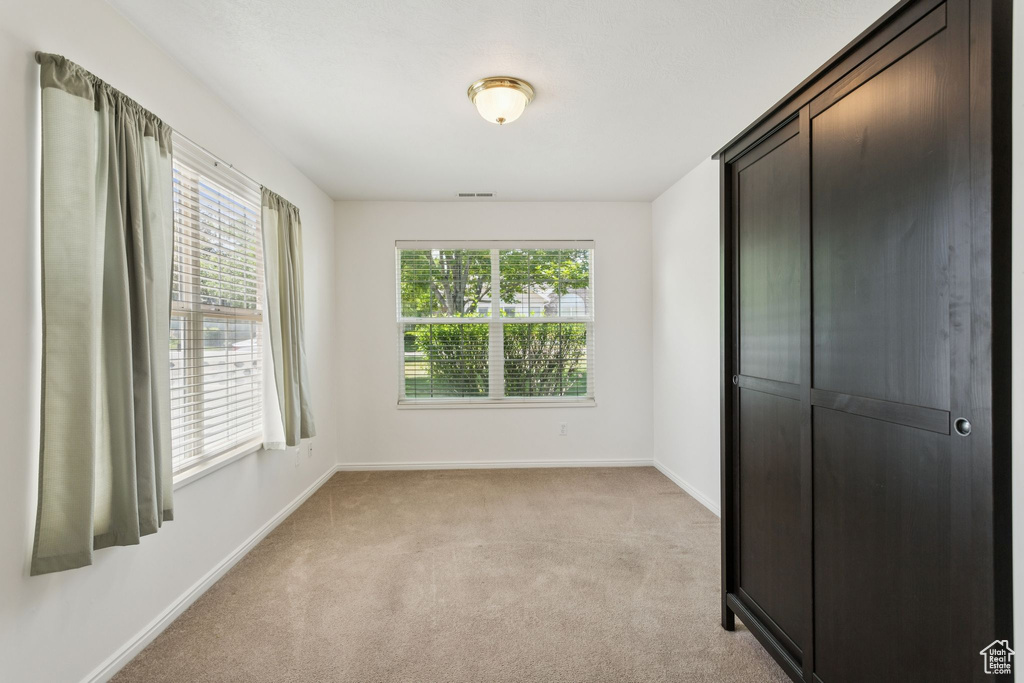 Unfurnished bedroom with light colored carpet and baseboards