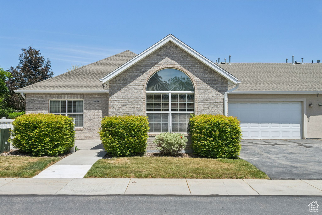 Single story home with an attached garage, driveway, and a shingled roof