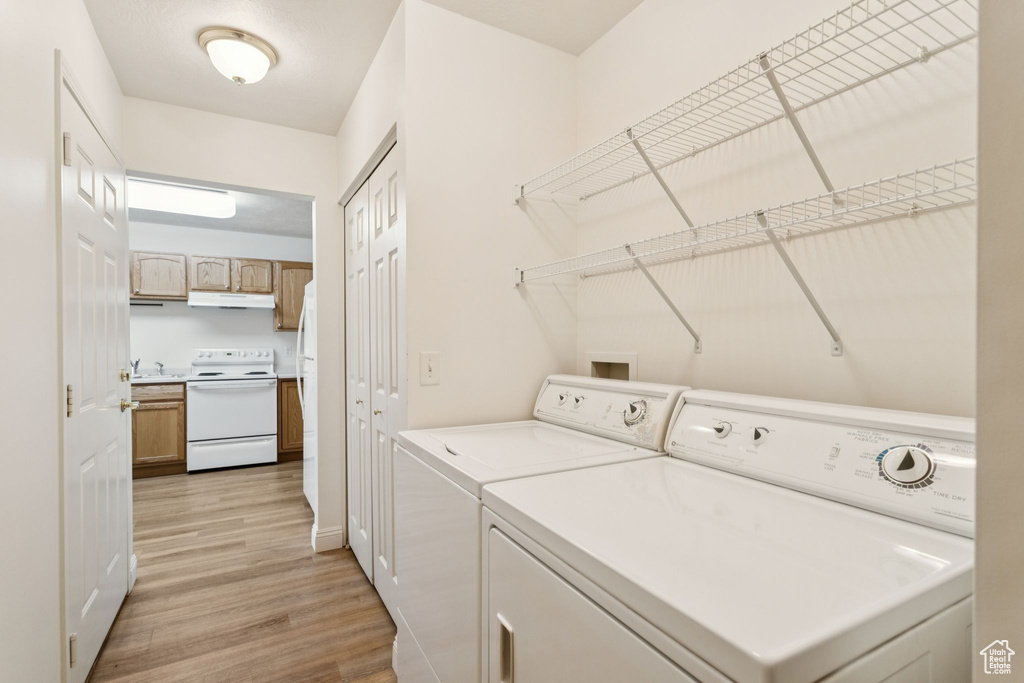 Laundry area featuring washing machine and clothes dryer, light wood-style floors, and baseboards