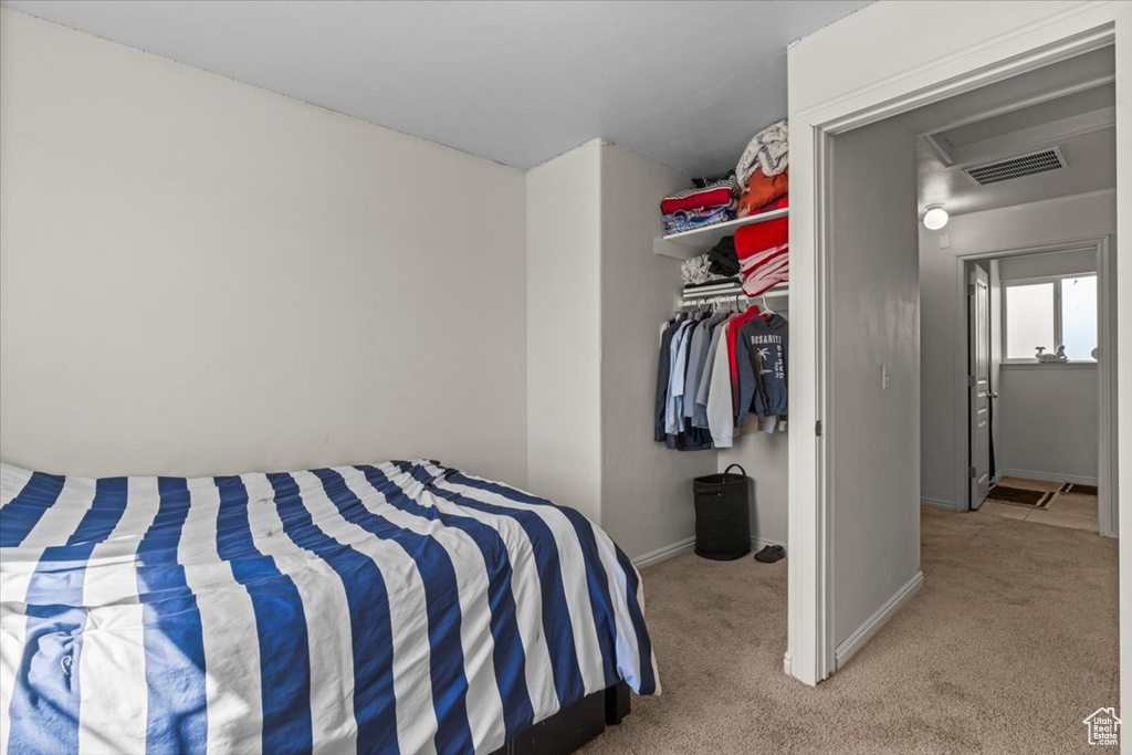 Bedroom with light colored carpet, baseboards, and a closet