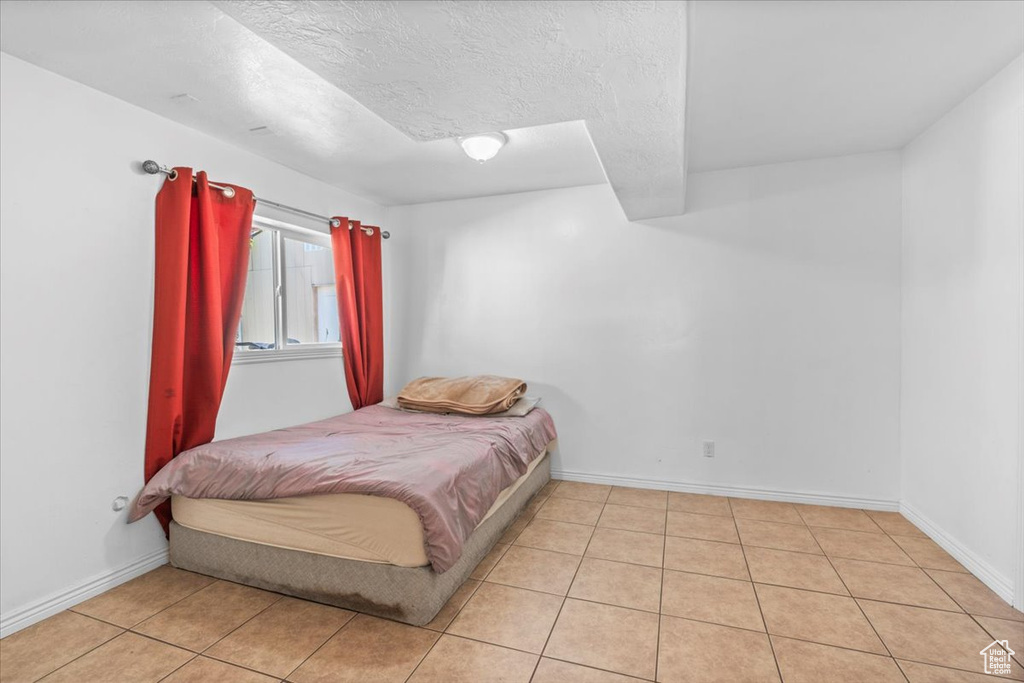 Bedroom with light tile patterned flooring, a textured ceiling, and baseboards