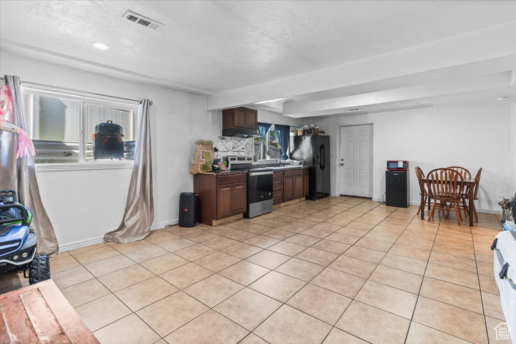 Kitchen featuring electric range, freestanding refrigerator, light tile patterned floors, a textured ceiling, and baseboards