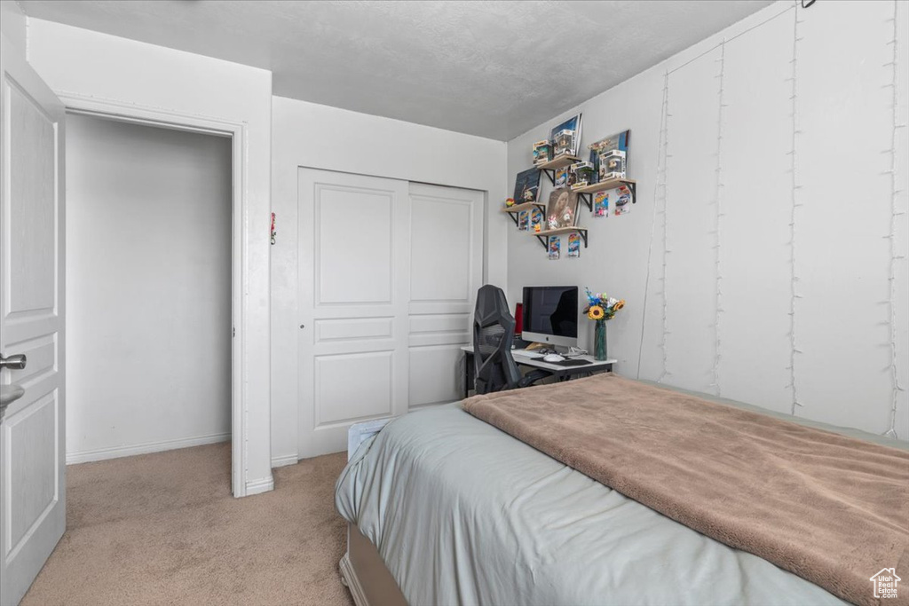 Bedroom featuring light carpet, a closet, and baseboards