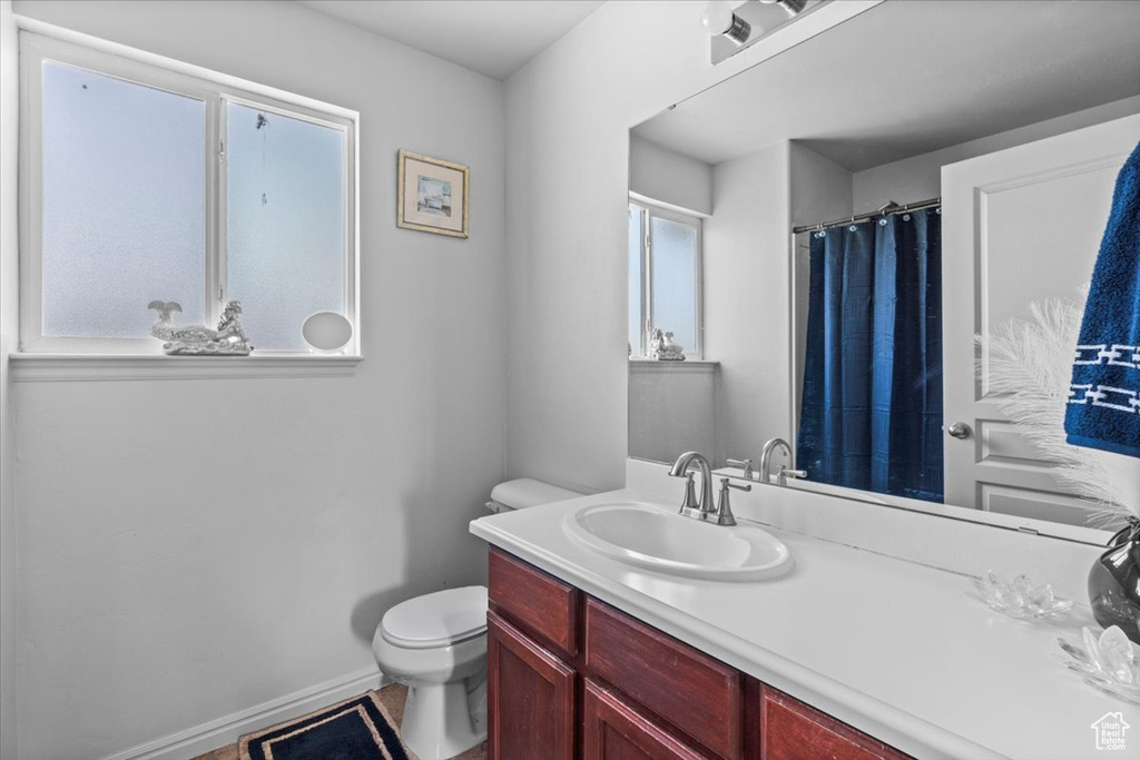 Full bathroom with toilet, vanity, and baseboards