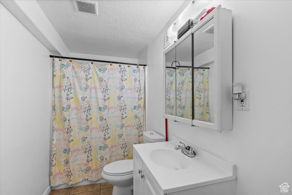 Full bath featuring vanity, toilet, a textured ceiling, tile patterned flooring, and a shower with shower curtain