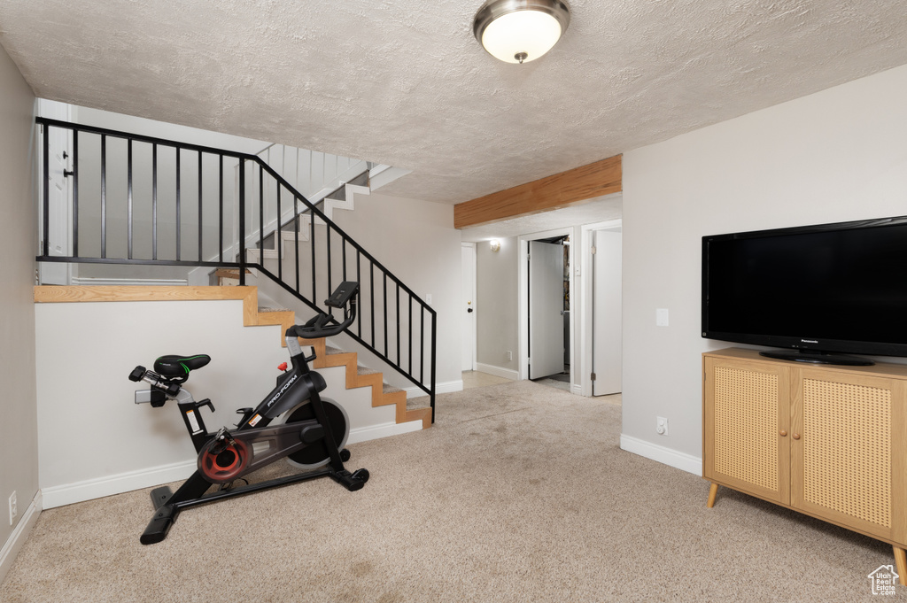 Workout room with carpet floors, baseboards, and a textured ceiling