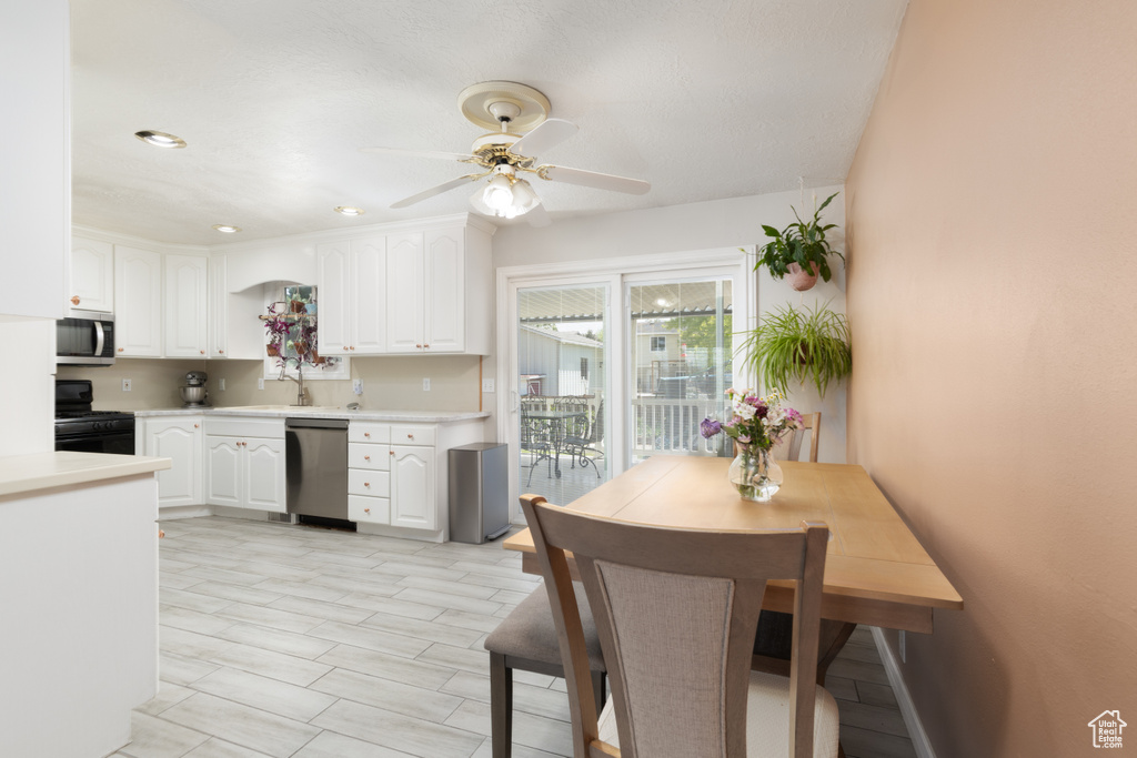Kitchen featuring stainless steel appliances, ceiling fan, light countertops, white cabinetry, and recessed lighting