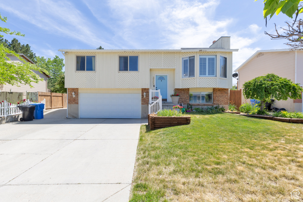 Bi-level home with brick siding, an attached garage, and driveway
