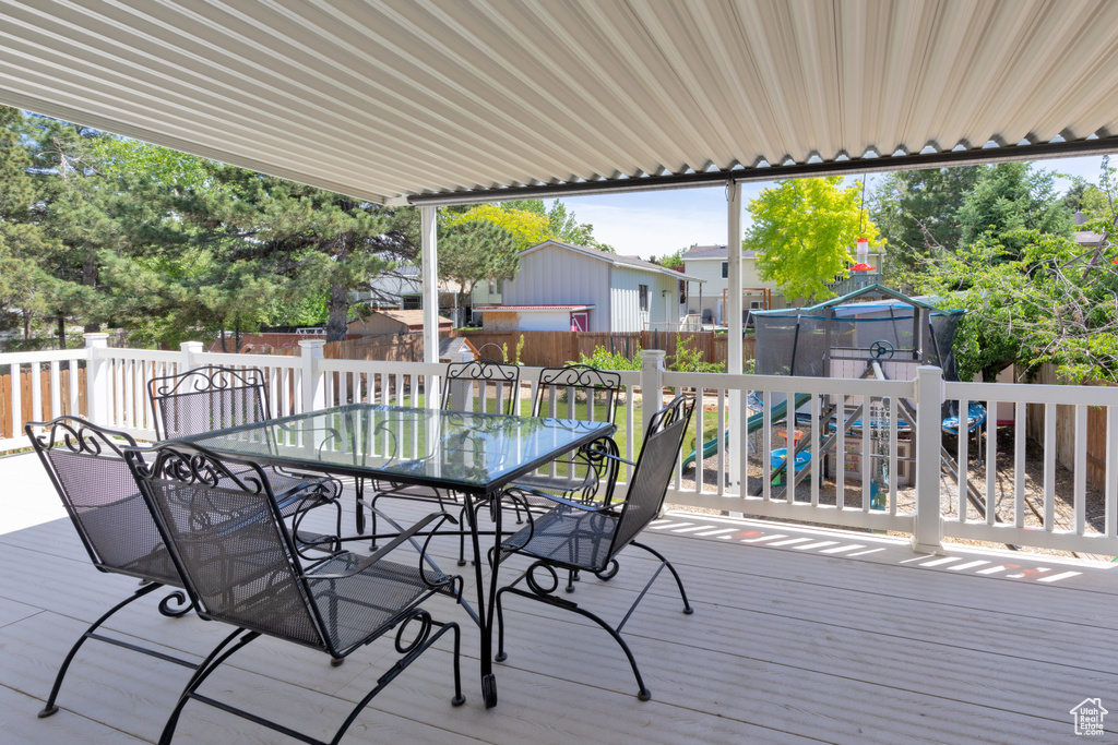 Deck with outdoor dining area, a trampoline, and a fenced backyard