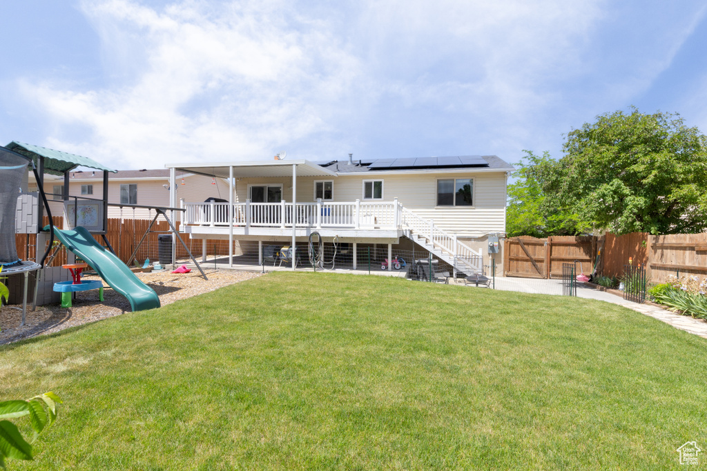 Rear view of house featuring stairway, a wooden deck, a playground, and solar panels