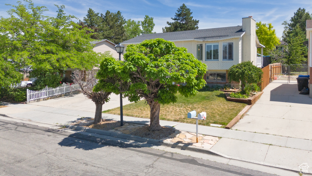 View of property hidden behind natural elements featuring driveway and a chimney