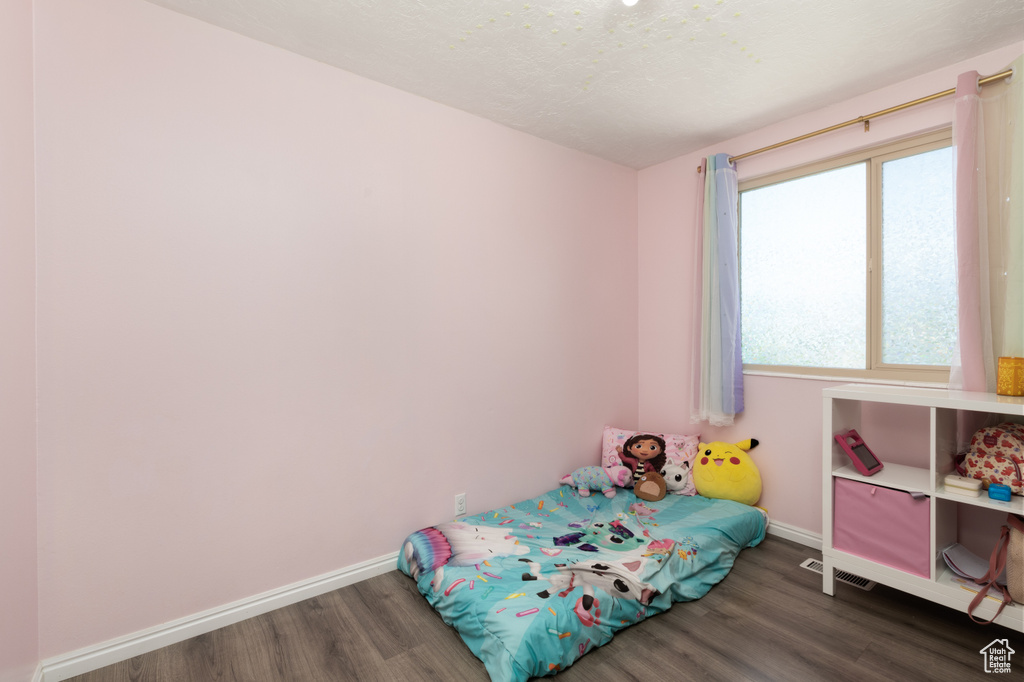 Bedroom with wood finished floors, baseboards, and a textured ceiling