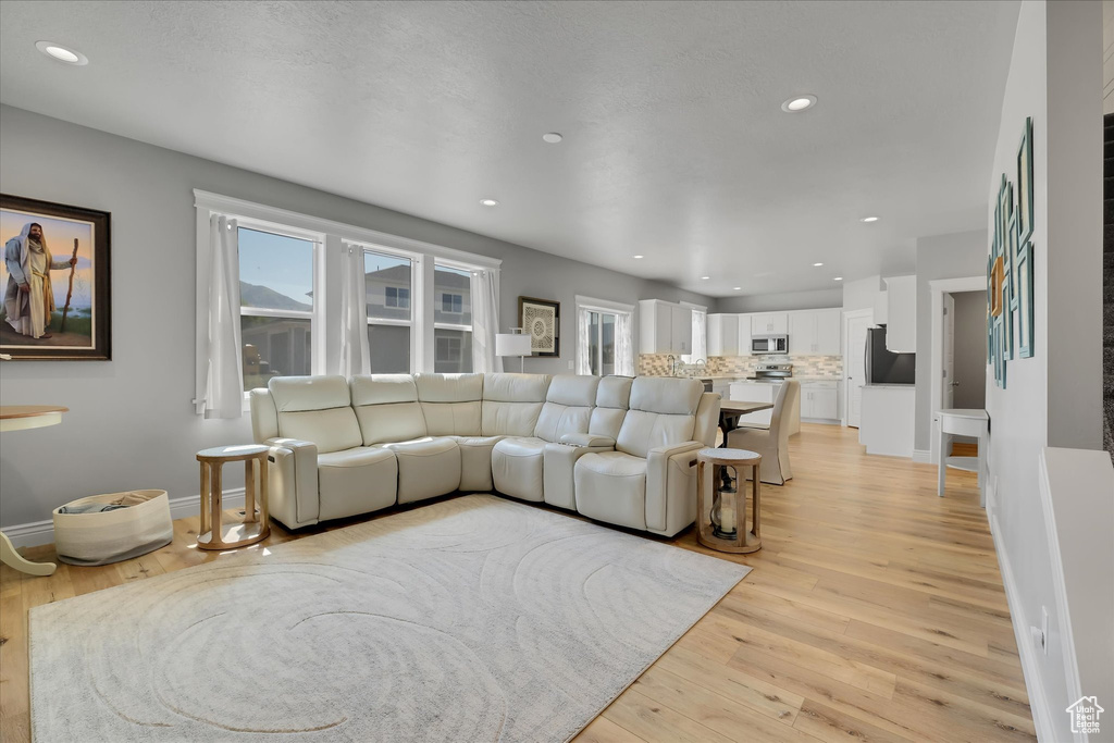 Living area with light wood finished floors, recessed lighting, and baseboards