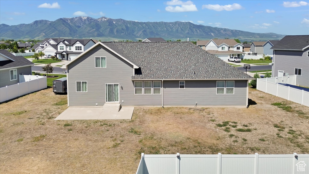 Back of house featuring a patio area, a residential view, a mountain view, and a fenced backyard