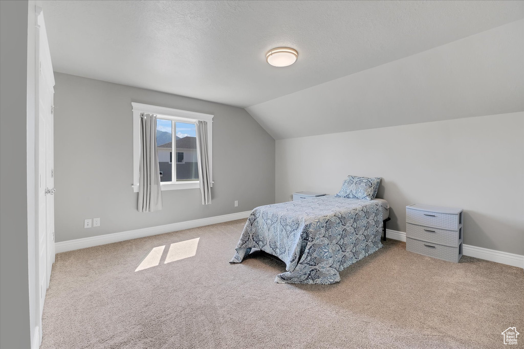 Carpeted bedroom with vaulted ceiling and baseboards