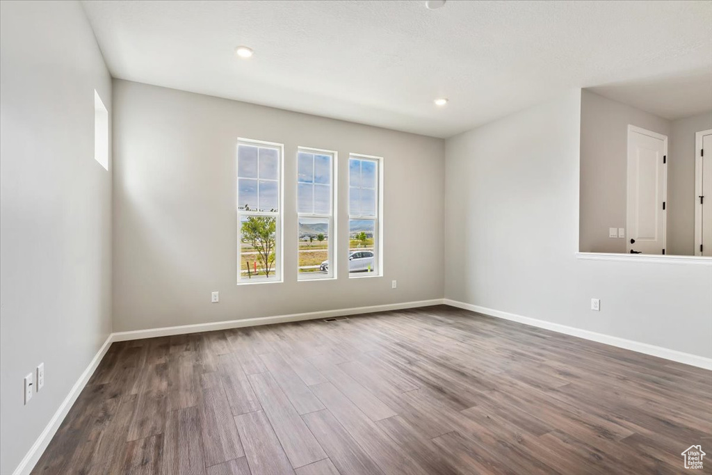Spare room featuring dark wood-style floors, baseboards, and recessed lighting