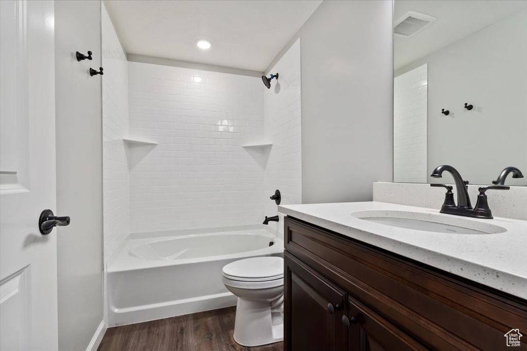 Bathroom featuring vanity, wood finished floors, toilet, and  shower combination