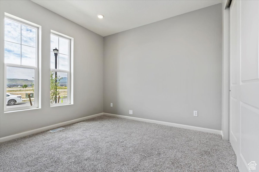 Unfurnished room featuring carpet floors, plenty of natural light, and baseboards