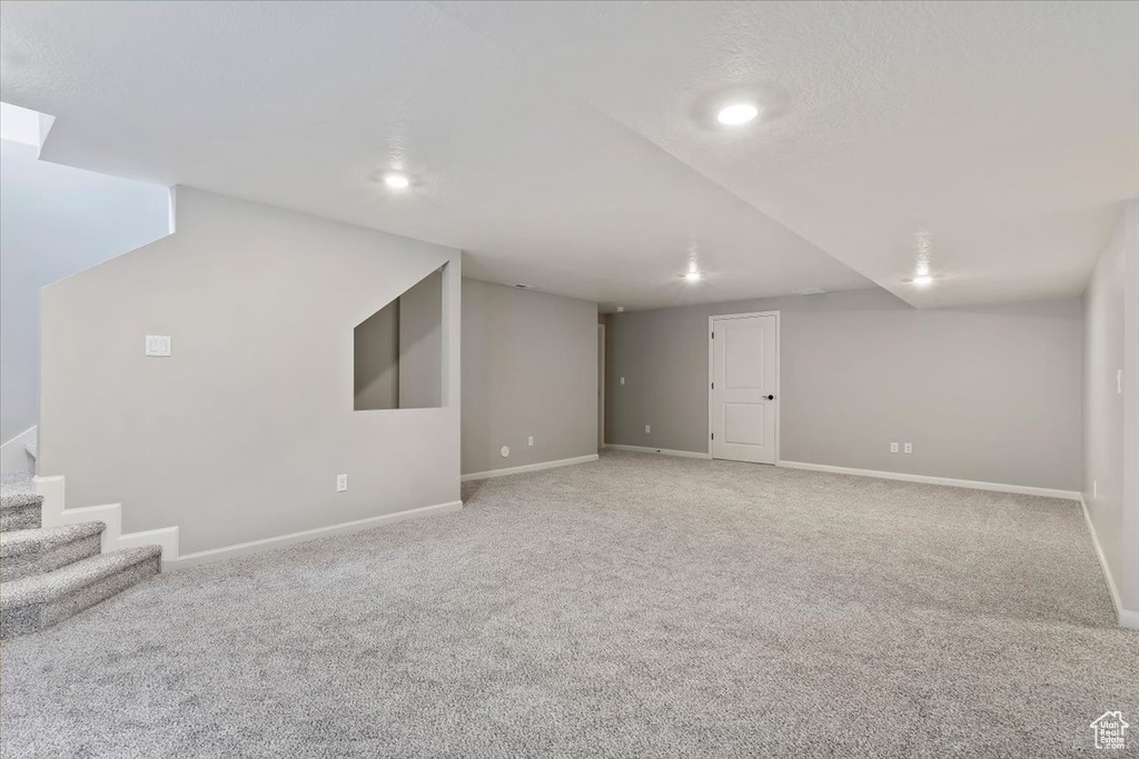 Finished basement featuring carpet floors, baseboards, recessed lighting, and stairway