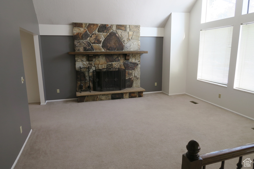 Carpeted living area with vaulted ceiling, a fireplace, and baseboards