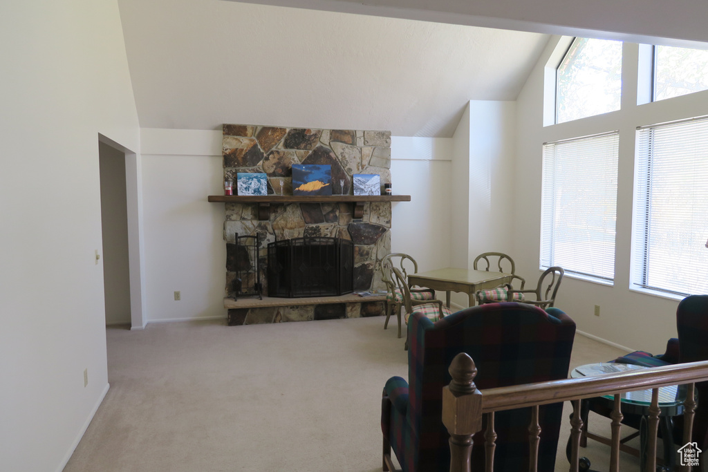Carpeted living room featuring lofted ceiling, plenty of natural light, a stone fireplace, and baseboards