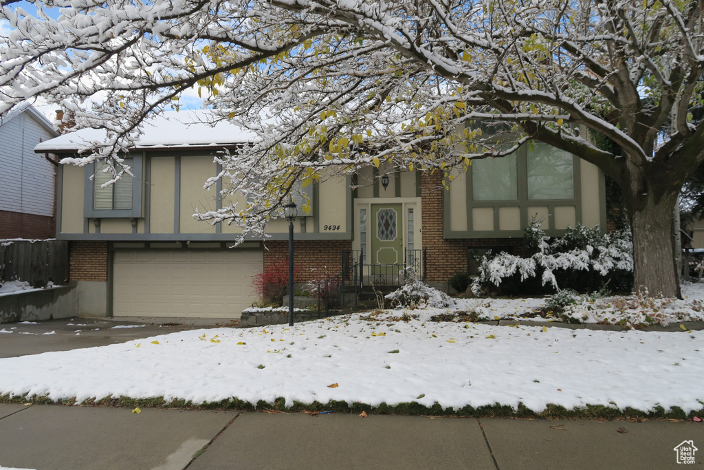 View of front facade with a garage, brick siding, and stucco siding