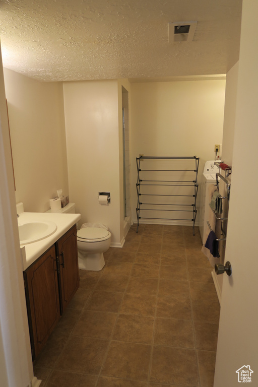 Full bath with vanity, toilet, washer / dryer, a textured ceiling, and a shower stall