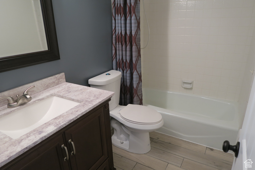 Full bath featuring vanity, toilet, shower / bath combo with shower curtain, and wood finished floors