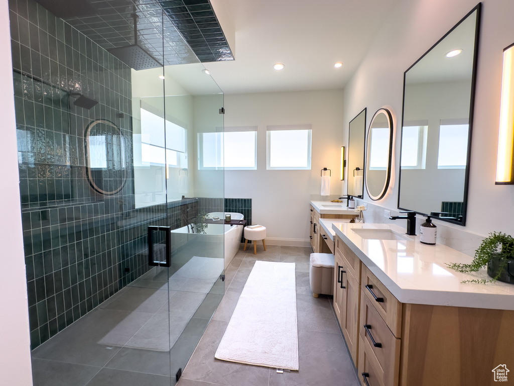 Bathroom featuring healthy amount of natural light, a soaking tub, double vanity, a shower stall, and recessed lighting