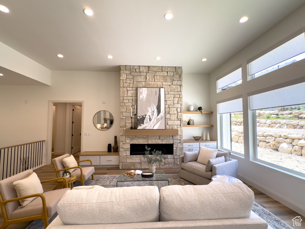 Living room featuring wood finished floors, recessed lighting, a stone fireplace, and baseboards